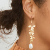 Lange guld blomsterøreringe med perlevedhæng – elegant og luksuriøst design