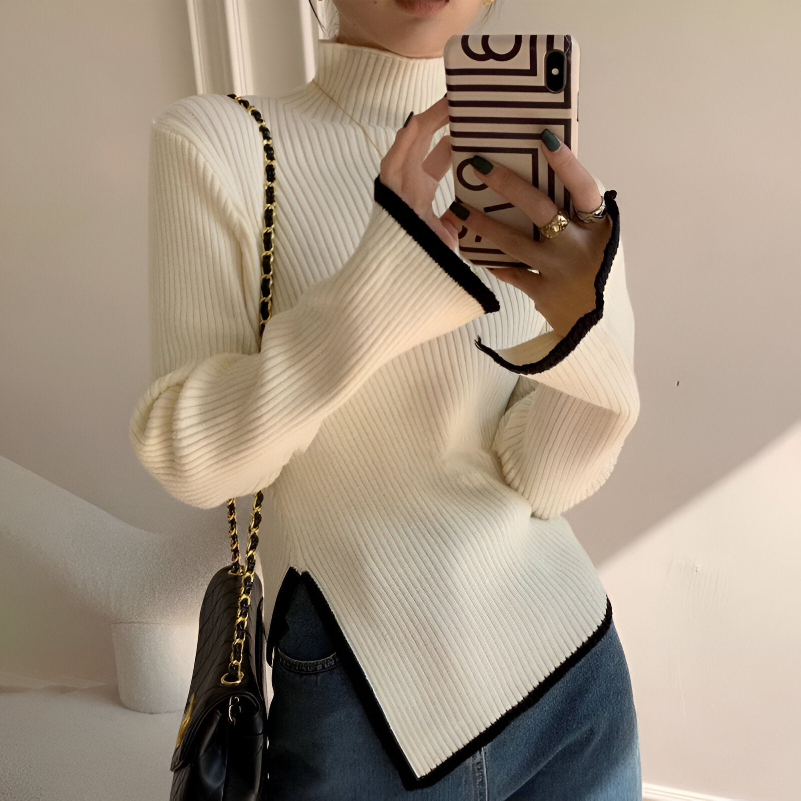 Elegant sort ribstrikket bluse med hvide kanter og asymmetrisk detalje