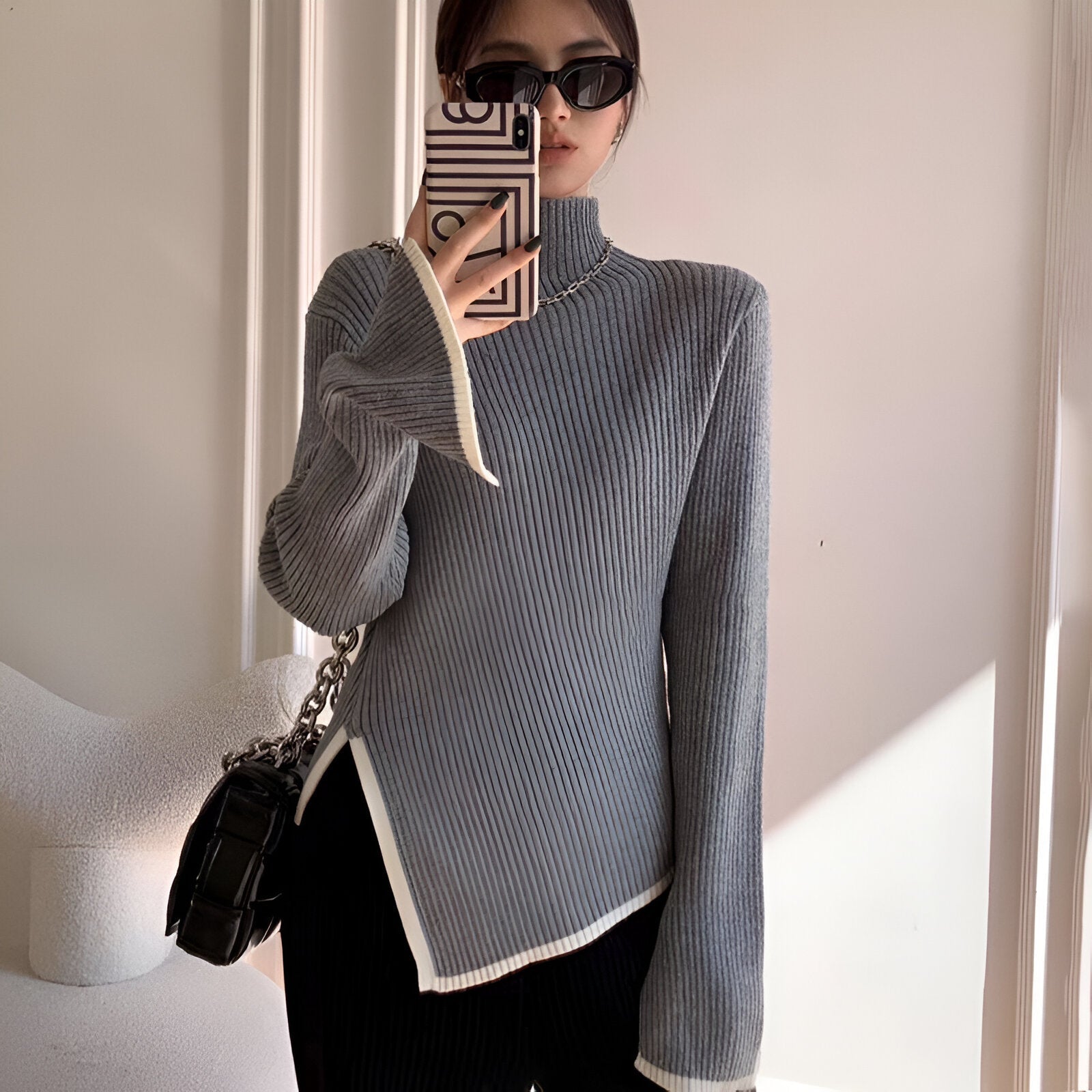 Elegant sort ribstrikket bluse med hvide kanter og asymmetrisk detalje
