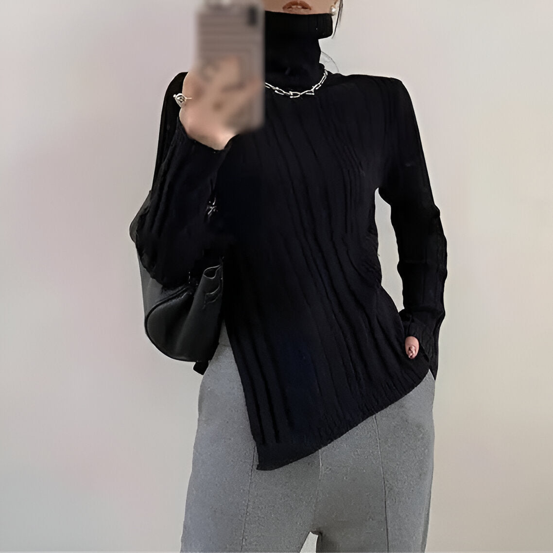 Elegant sort ribstrikket bluse med hvide kanter og asymmetrisk detalje