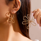 Guld blomsterøreringe i tråddesign – moderne og elegant statement-smykke