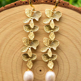Lange guld blomsterøreringe med perlevedhæng – elegant og luksuriøst design