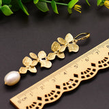 Lange guld blomsterøreringe med perlevedhæng – elegant og luksuriøst design